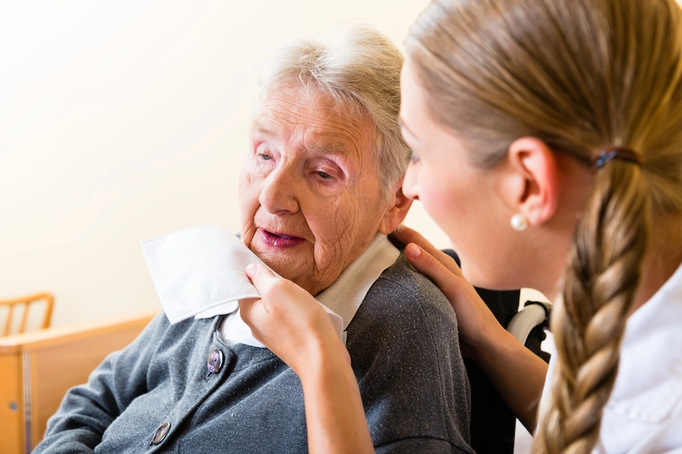 Nurse wiping mouth of senior woman in nursing home