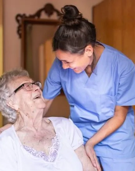 Happy Senior woman laughing with her caregiver at home. Senior home care concept.