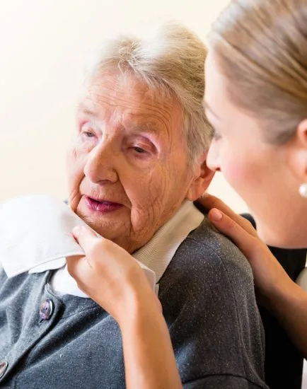 Nurse wiping mouth of senior woman in nursing home
