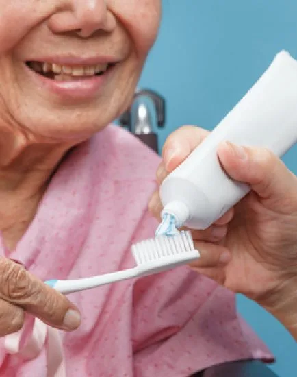 Caregiver take care asian elderly woman while using toothbrush.
