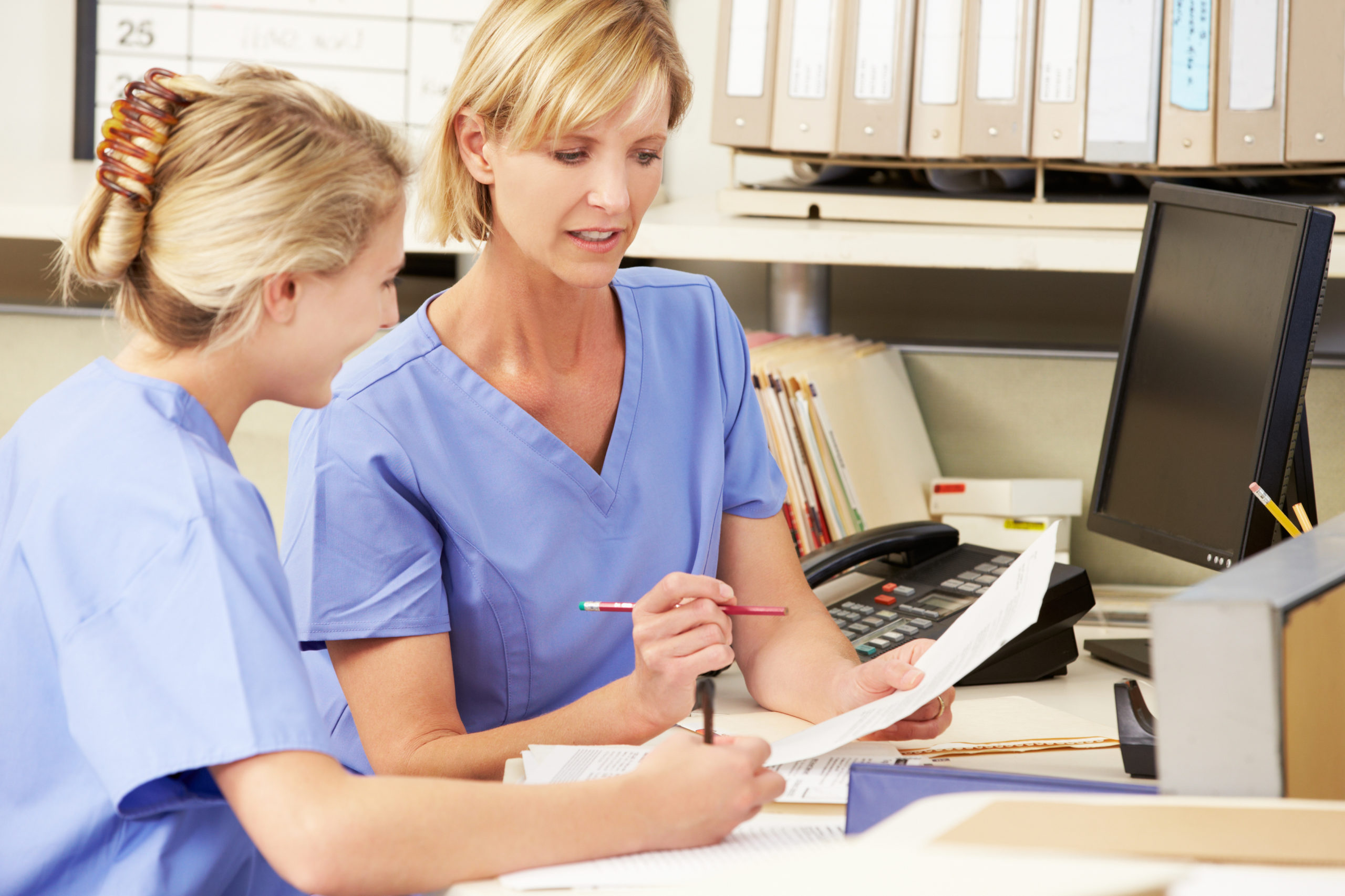 Two Nurses Working At Nurses Station