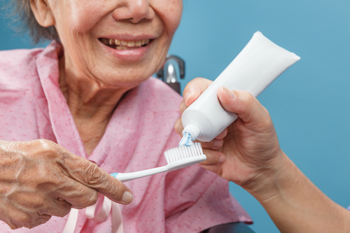Caregiver take care asian elderly woman while using toothbrush.