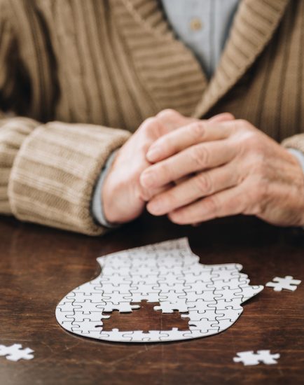 cropped view of senior man playing with puzzles on table