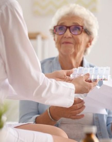 Doctor giving medicine and instruction to senior woman at home