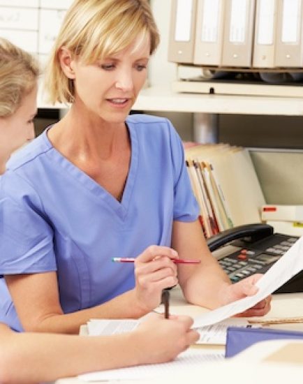 Two Nurses Working At Nurses Station