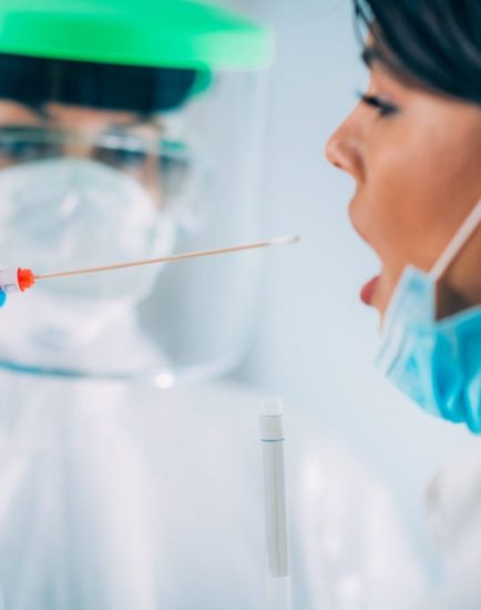 Coronavirus test. Medical worker in protective suite taking a swab for corona virus test, potentially infected young woman