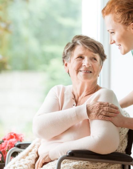 Young nurse helping an elderly woman in a wheelchair. Nursing home concept